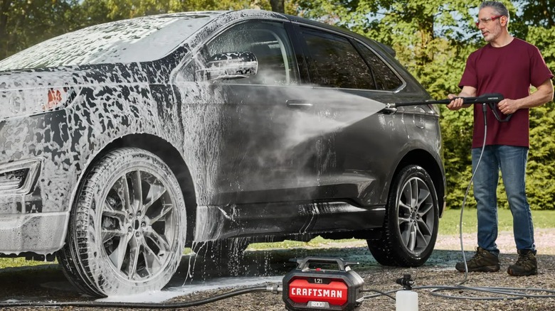 A person using a Craftsman pressure washer on a car.