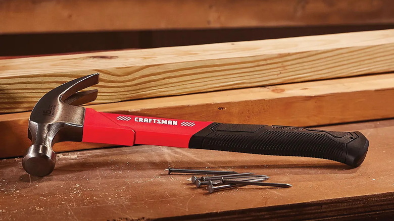 Craftsman 16-ounce fiberglass claw hammer laying on a work table with a pile of nails