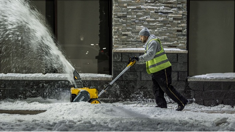 A person using a DeWalt electric snow blower.