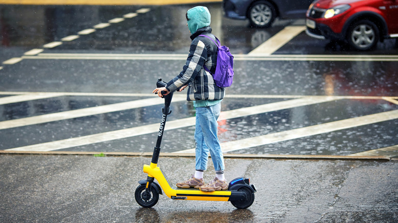Woman riding electric push scooter while raining