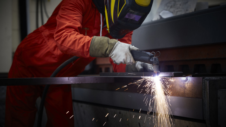 Masked worker using a plasma cutter