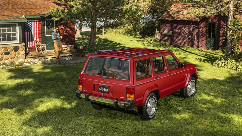1984 Jeep Cherokee parked on grass in front of cabin home