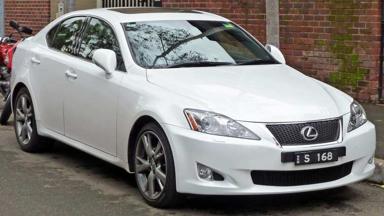 White 2010 Lexus IS 250 parked on a paved surface next to a  building