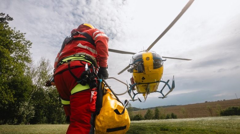 Yellow rescue helicopter landing in field with worker