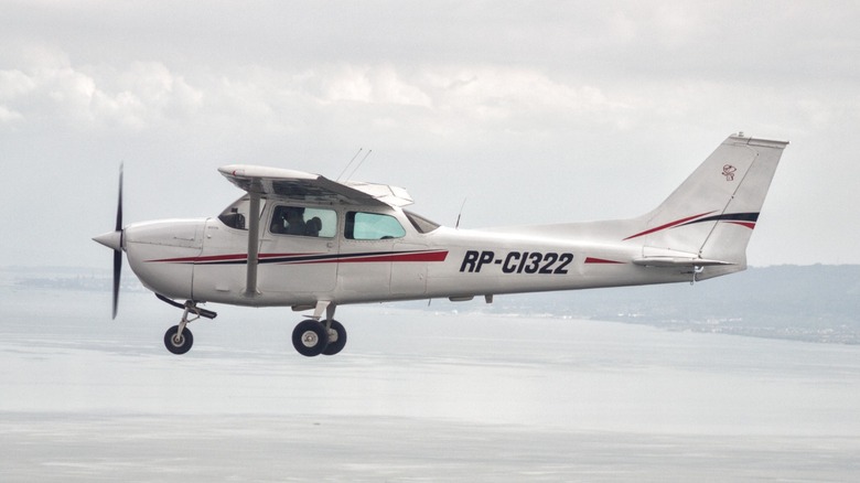 a Cessna 172 flying over a bay