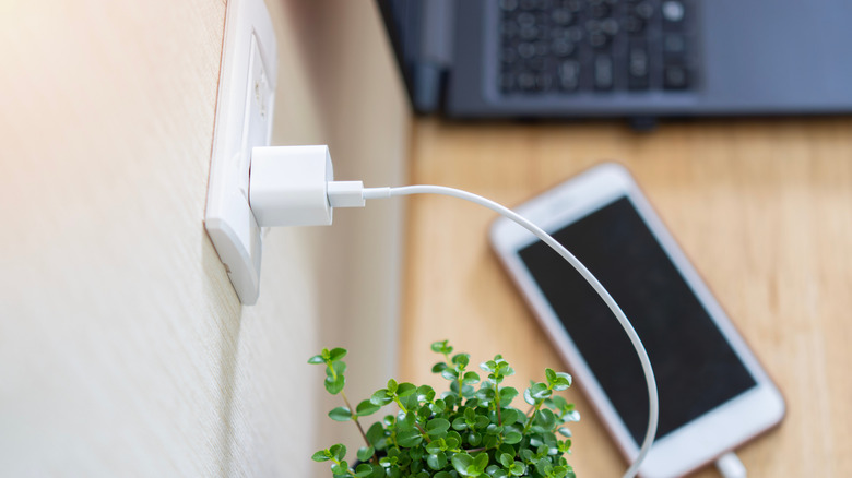 Phone charger plugged into wall connected to phone on table