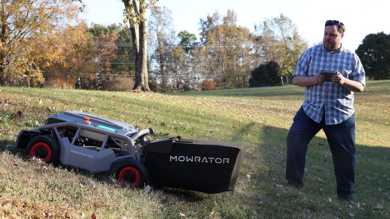 a man controlling a  lawn mower to trim grass on a slope