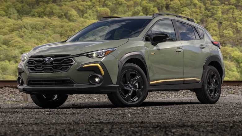 Subaru Crosstrek Sport parked on a gravel surface next to railroad tracks