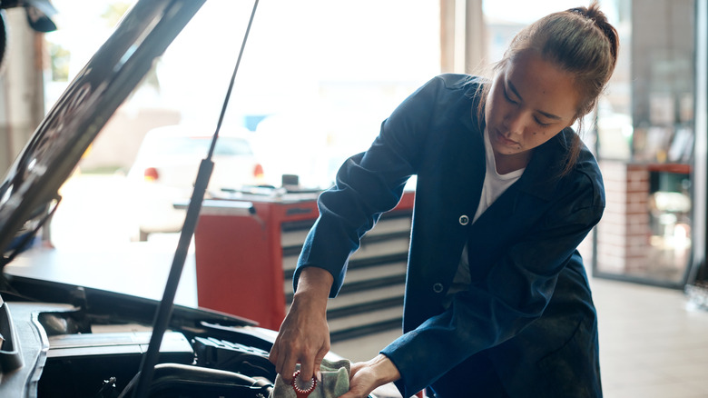 Woman in machine shop changing out oil