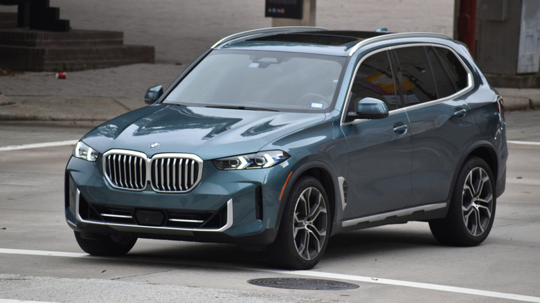 A blue BMW X7 on a paved road.