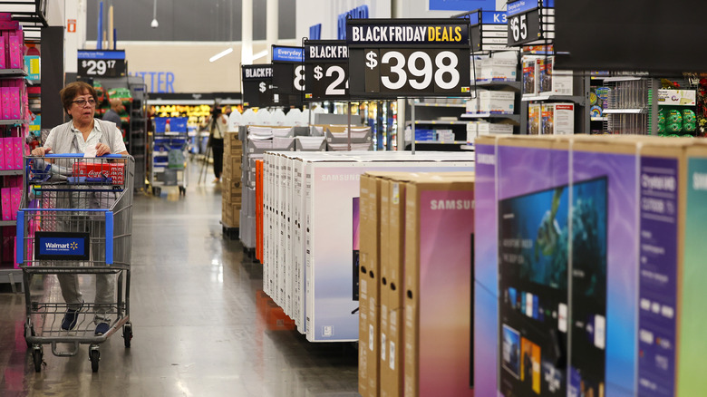 A female shopper pushes a cart while walking the TV aisle at Walmart on Black Friday.