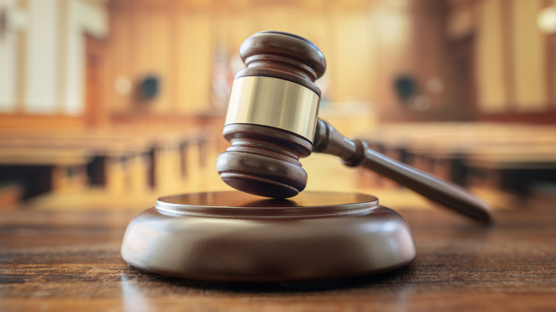 A gavel in focus while the courtroom in the background is out of focus.