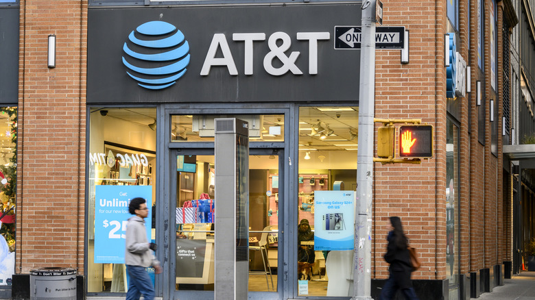 People walking in front of a brick AT&T store on a city street