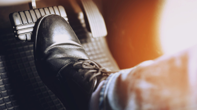 A person pressing down on a vehicles brake pedal