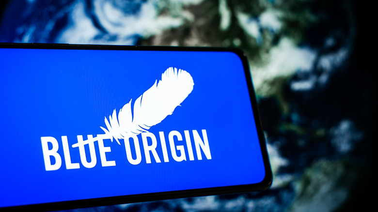 Blue Origin logo on smartphone screen with blurred Earth in background