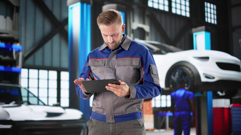 mechanic standing in front of car on lift
