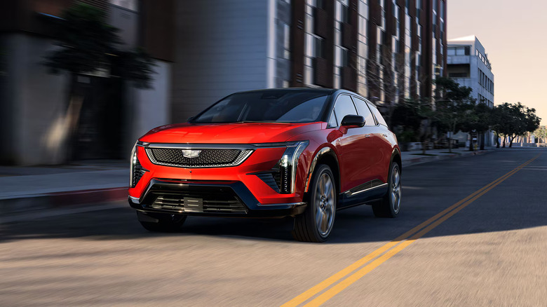 2026 red Cadillac Optiq-V EV SUV driving on city street