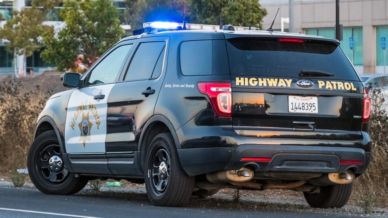 Rear 3/4 view of California Highway Patrol Ford Explorer on side of road with flashing lights on