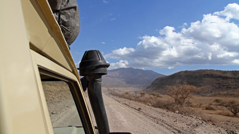 A snorkel intake attached to a vintage Toyota Land Cruiser driving on a sandy track