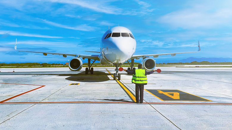A ramp agent guides an airplane at an airport
