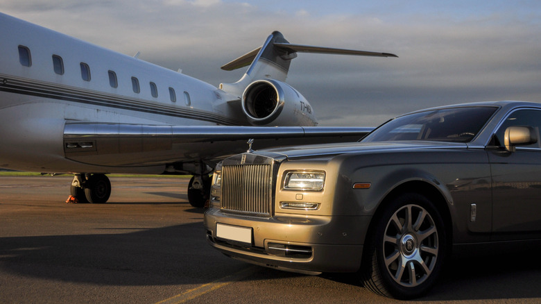 A Rolls Royce Phantom luxury car photographed together with a private executive airplane at an airport.
