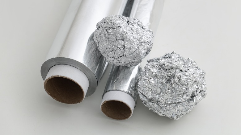 Rolled aluminum foil with crumpled pieces.
