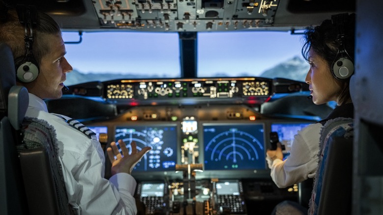 Pilots in the cockpit talking to each other with flight instruments on the dash
