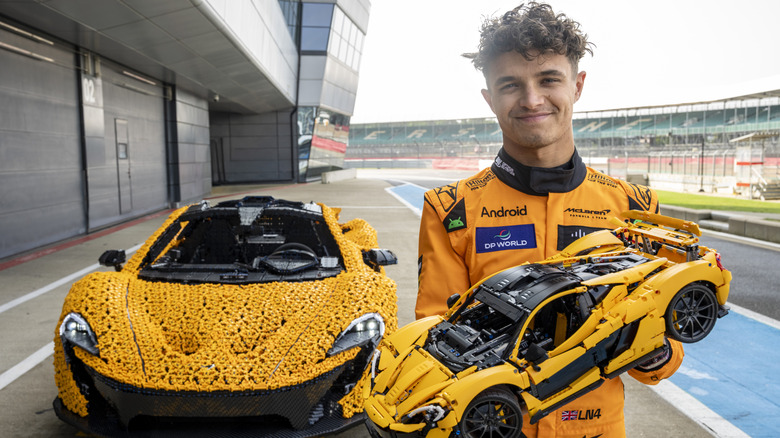 Lando Norris holding small McLaren LEGO car next to Full Size Lego McLaren