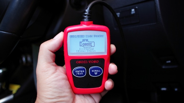 a person holding a basic red obdii scan tool