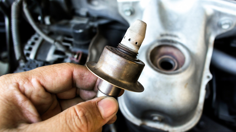 Technician holding removed O2 sensor