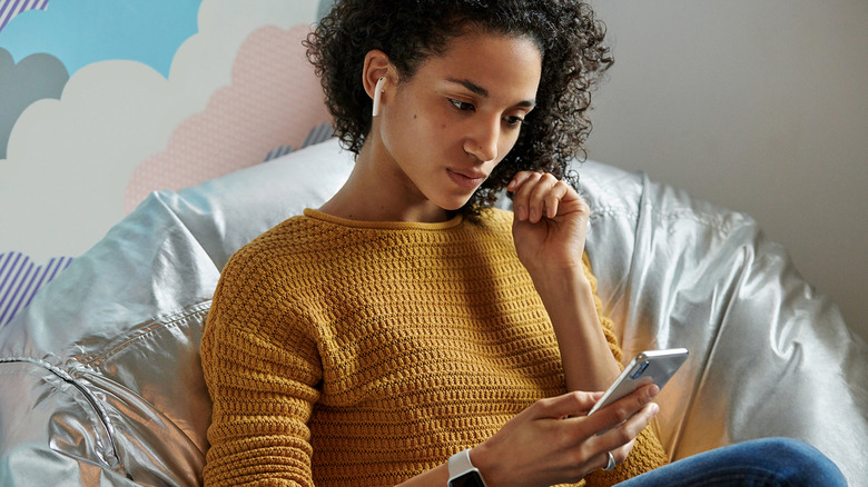 Woman with AirPods in ears and using an iPhone