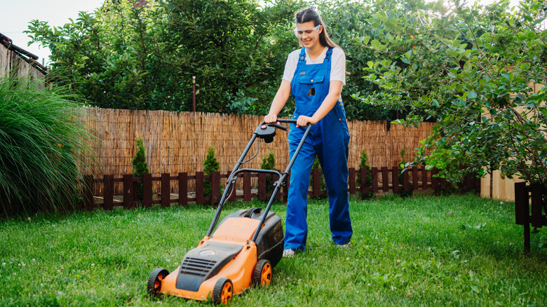 Woman mowing her lawn with orange mower