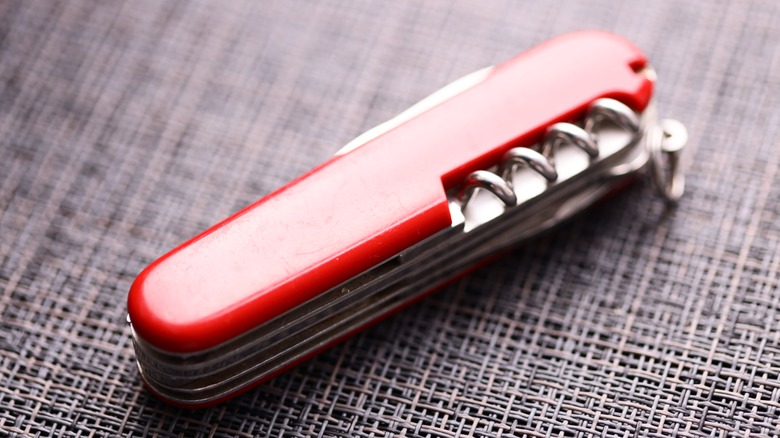 A Swiss Army knife sitting on a woven table.