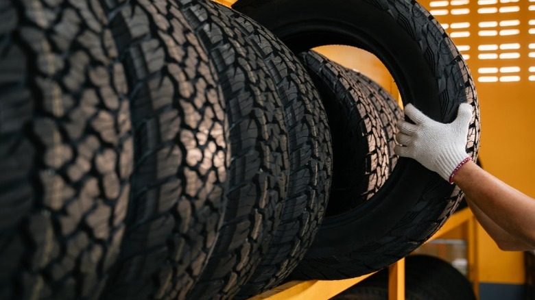 A person grabbing a tire off a shelf of tires on display