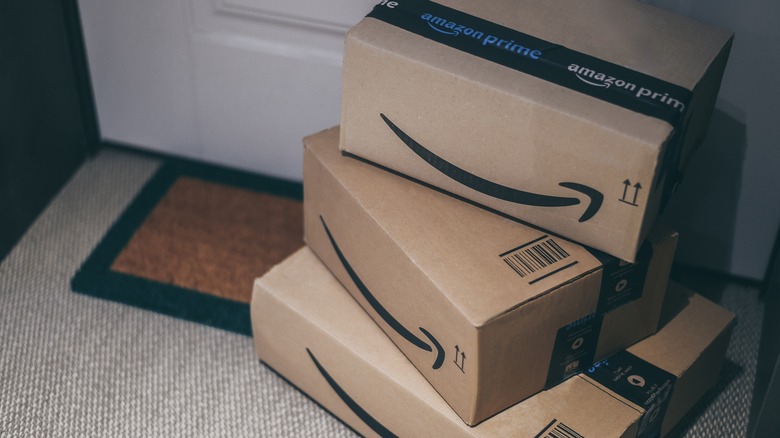 Three Amazon packages stacked in front of a door
