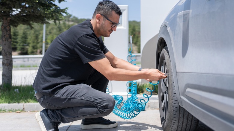 A person putting air into their car's tires