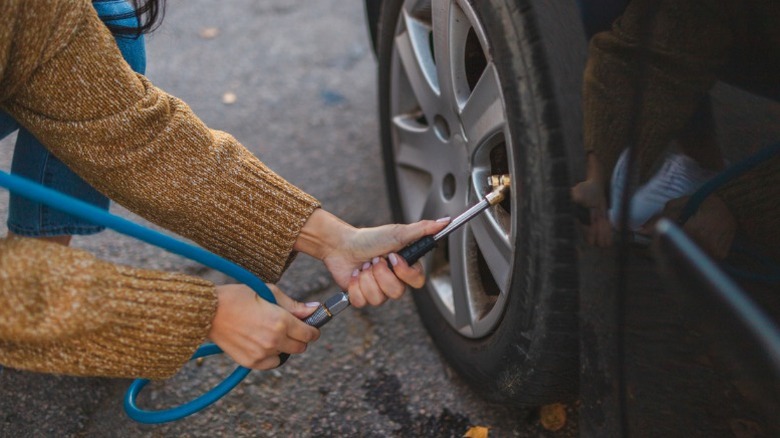A person putting air in their car's tires
