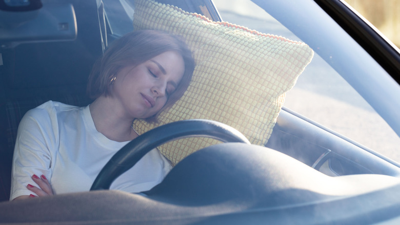 Woman sleeps on pillow in her car