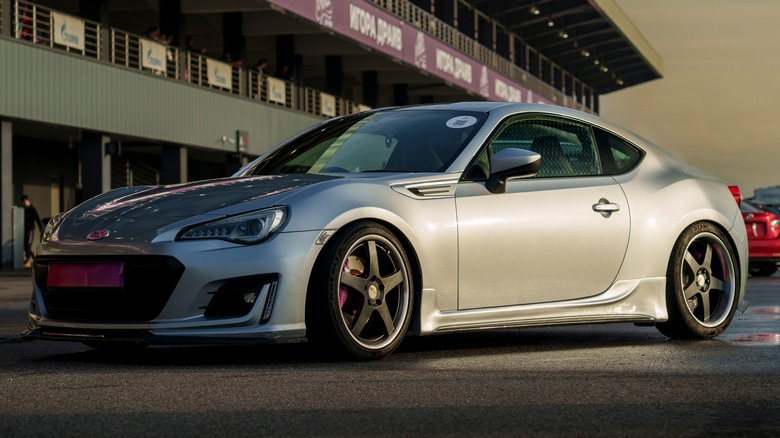 A modified silver Toyota sports car on a track with aftermarket wheels.