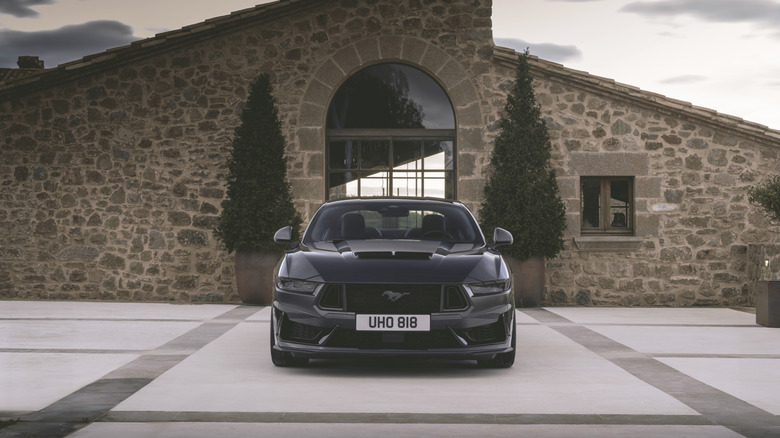 The front of a Ford Mustang Dark Horse outside a luxury home