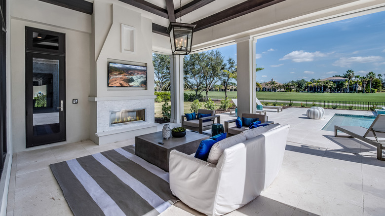 A Covered Patio With Furniture And A Mounted Flat Screen TV