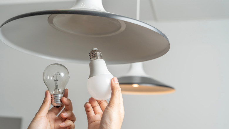 People replacing an incandescent bulbs with LED bulb in a light fixture