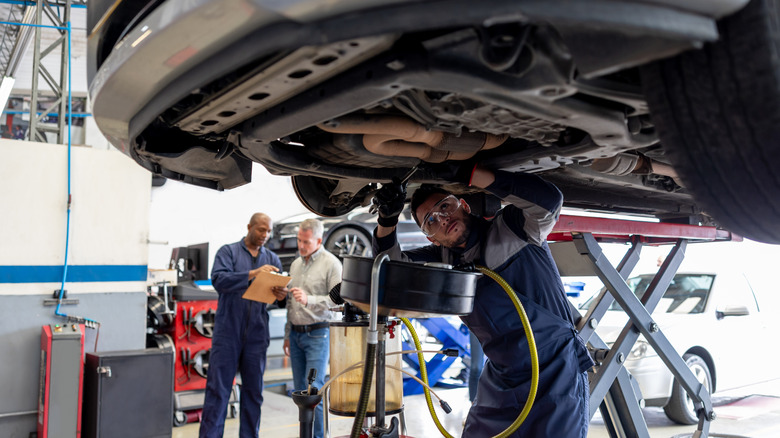 Mechanic drains the oil from car engine