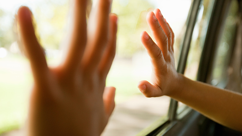 Flat hands touching car window