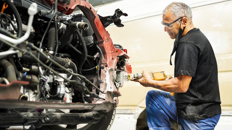 Worker using grinder to repair rust from a car frame
