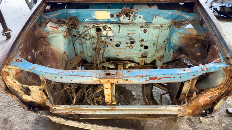 Rusted car frame with engine removed