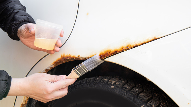 Man applying rust treatment to a car