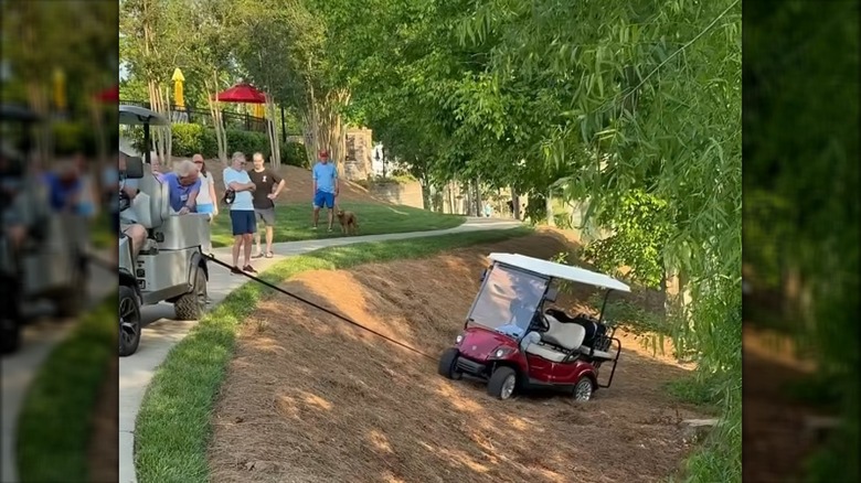 A Golf Cart Towing Another Cart Stuck In A Ditch