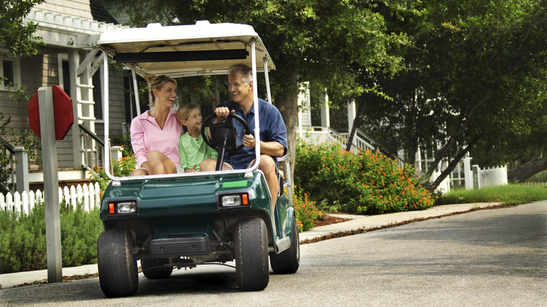A Family Traveling Through A Community By Golf Cart