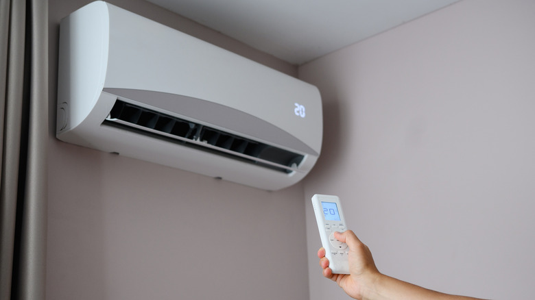 Person altering air conditioner temperature with remote control